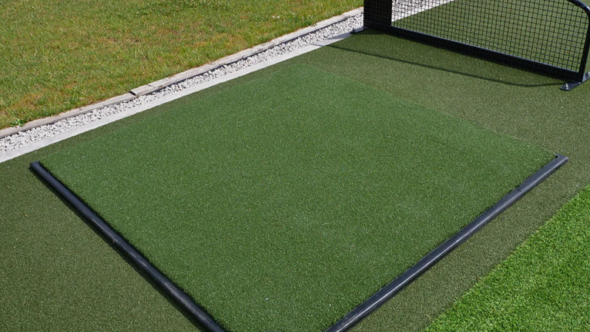 Freestanding garden golf cage set up on a lawn close to the garden boundary