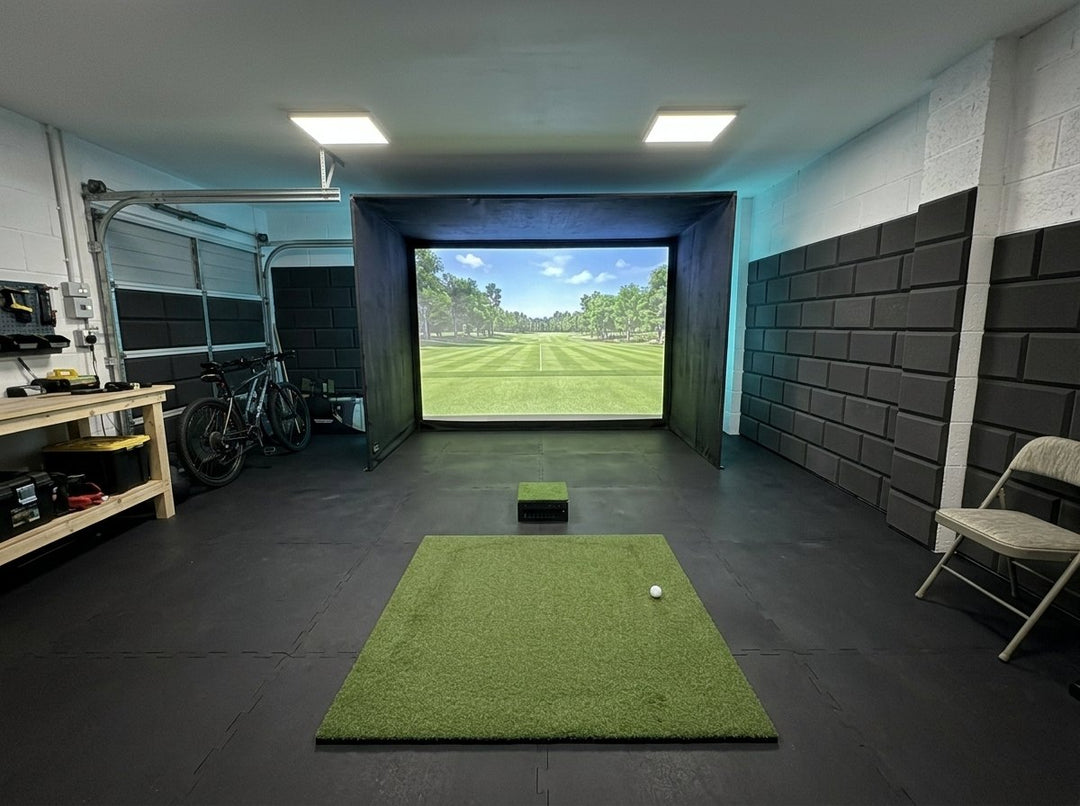 Illustration: golf simulator enclosure, hitting mat and a floor projector case in front of the mat in a UK double garage, LED strip lighting; black rubber flooring and black foam wall tiles