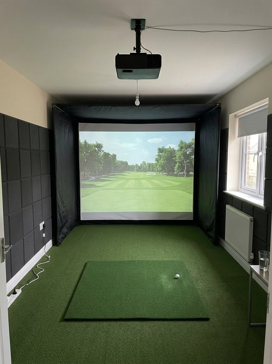 Illustration: golf simulator enclosure, hitting mat and a ceiling-mounted projector in a UK spare bedroom, daylight; artificial grass flooring and black foam wall tiles