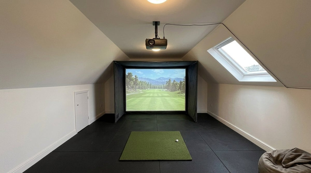 Illustration: golf simulator enclosure, hitting mat and a ceiling-mounted projector in a UK loft conversion, daylight; black rubber flooring