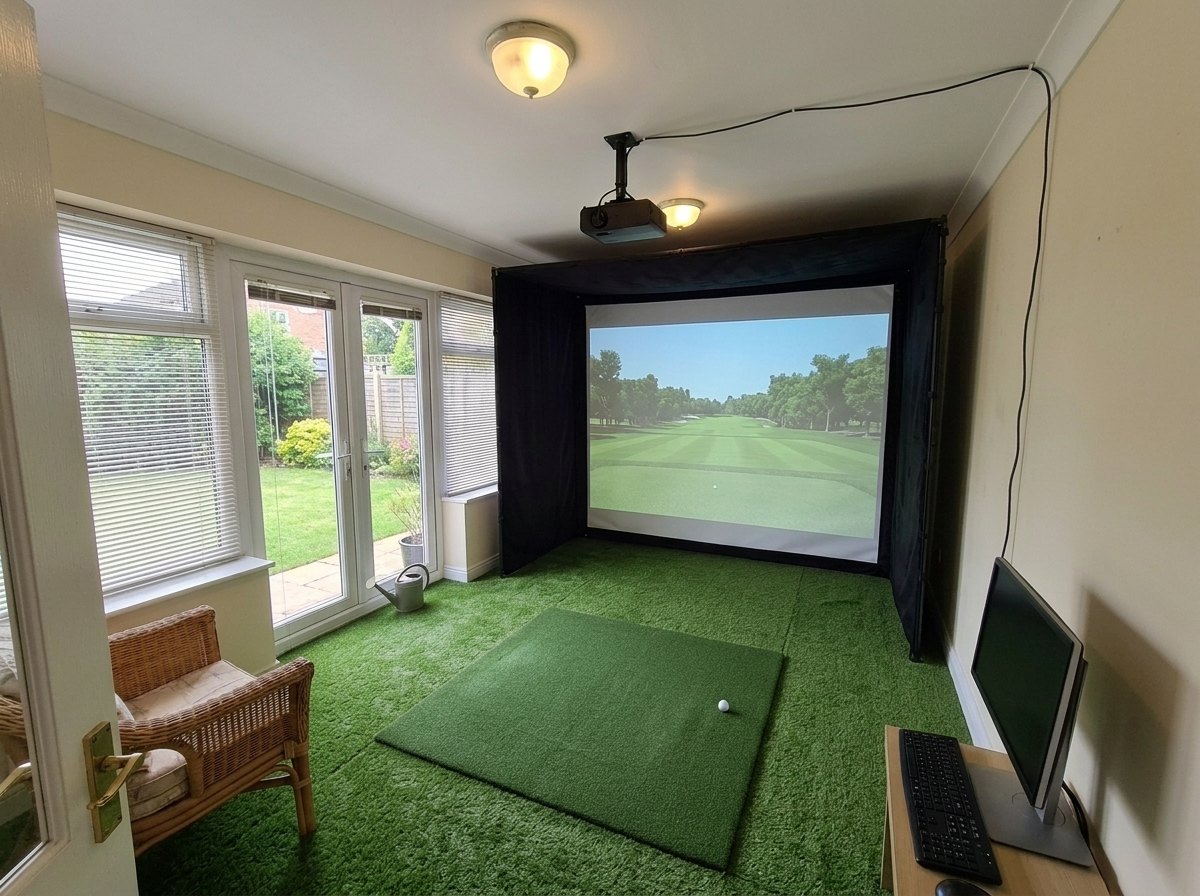 Illustration: golf simulator enclosure, hitting mat and a ceiling-mounted projector in a UK conservatory, daylight; artificial grass flooring