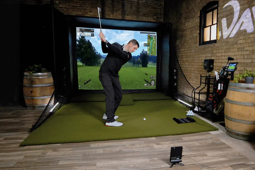 Golfzon WAVE golf simulator in action with projection screen and player mid-swing