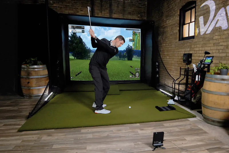 Golfzon WAVE golf simulator in action with projection screen and player mid-swing